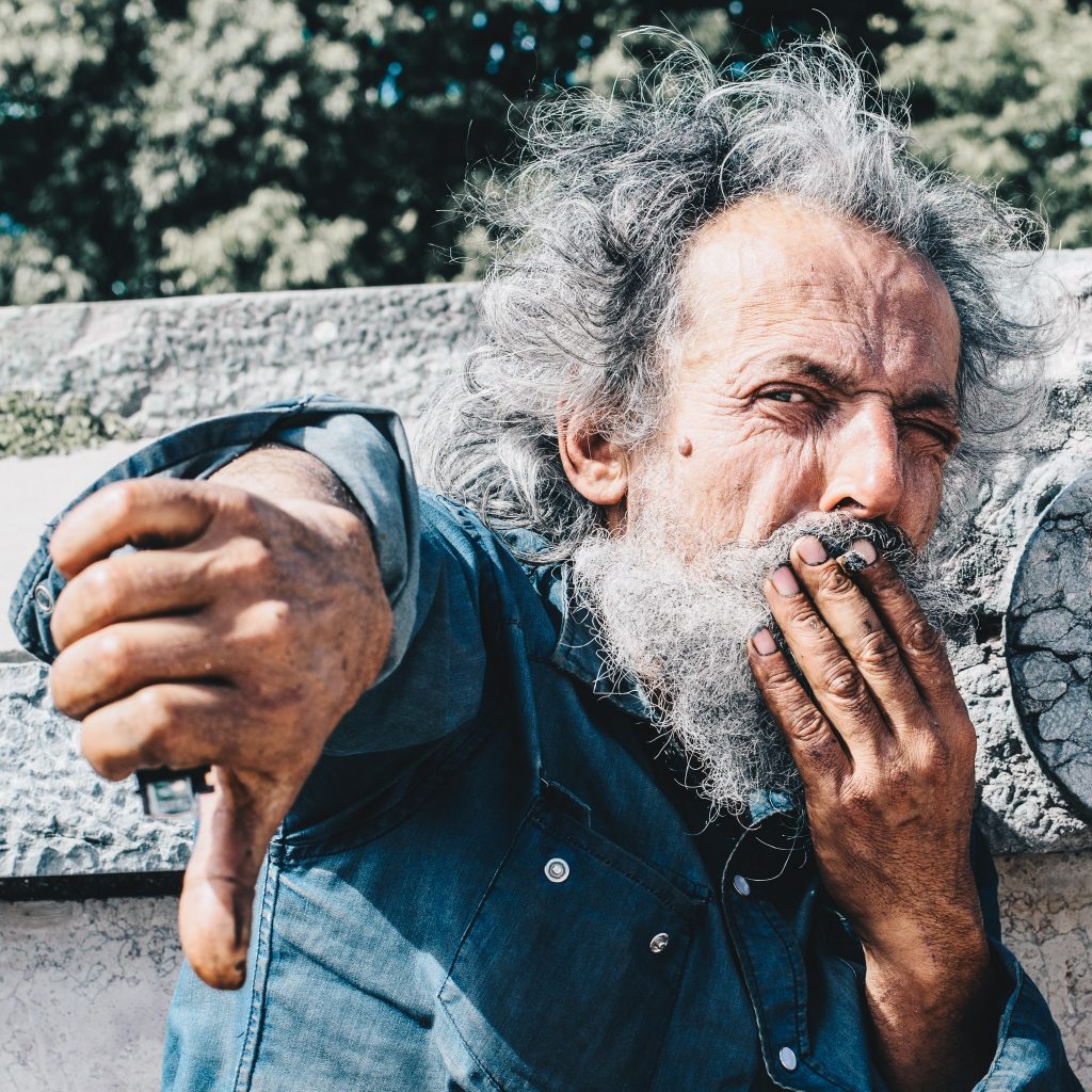 Un homme agé qui fume et met le pouce en bas